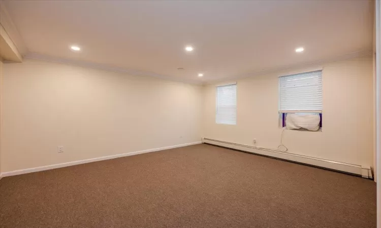 Carpeted empty room featuring a baseboard radiator and ornamental molding