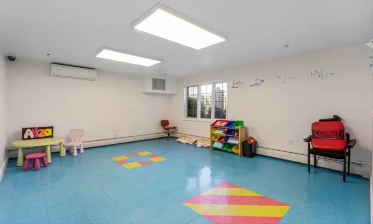 Rec room with an AC wall unit and baseboard heating