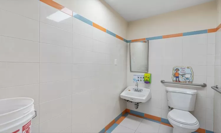 Bathroom with sink, tile walls, tile patterned floors, and toilet