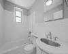 Full bathroom with tile walls, tiled shower / bath, vanity, and toilet