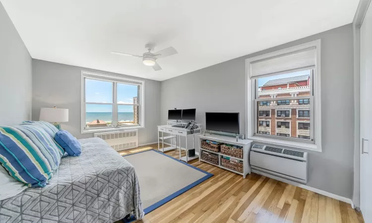 Bedroom featuring hardwood / wood-style flooring, radiator, heating unit, and ceiling fan