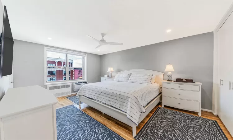 Bedroom featuring ceiling fan, radiator heating unit, and light hardwood / wood-style flooring