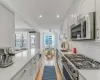 Kitchen featuring sink, stainless steel appliances, light hardwood / wood-style floors, light stone countertops, and white cabinets