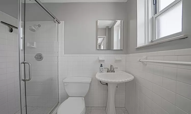 Bathroom featuring tile walls, toilet, and walk in shower