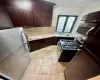 Kitchen featuring light tile patterned floors, sink, stainless steel appliances, dark brown cabinetry, and decorative backsplash