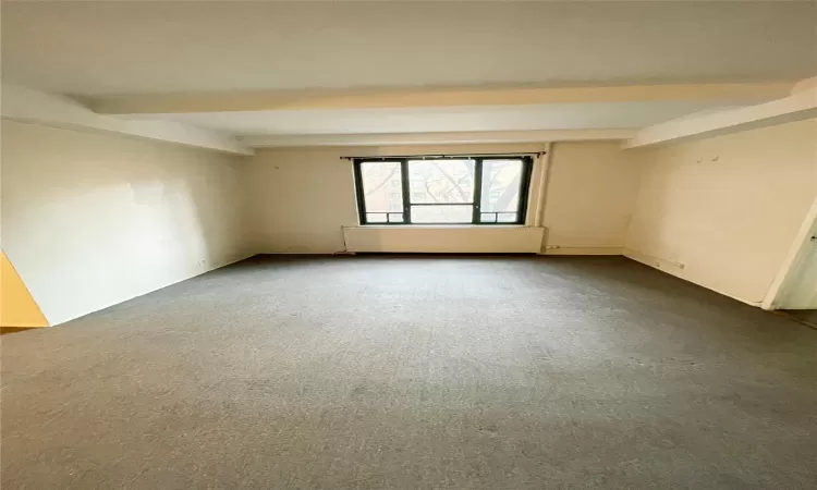 Spare room featuring carpet floors and beam ceiling