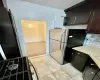 Kitchen with light tile patterned floors, dark brown cabinetry, backsplash, and stainless steel fridge