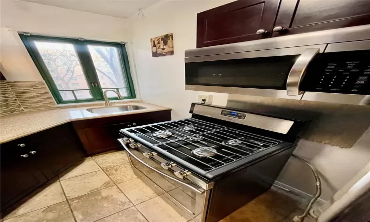 Kitchen featuring appliances with stainless steel finishes, sink, dark brown cabinets, and tasteful backsplash