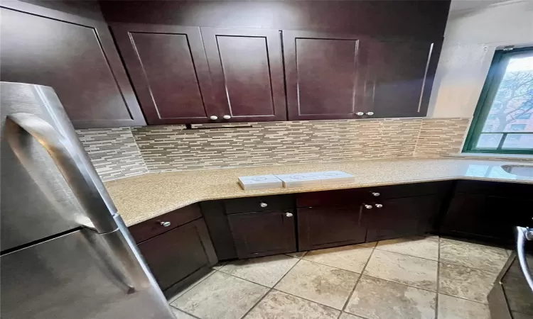 Kitchen with dark brown cabinetry, stainless steel fridge, and decorative backsplash