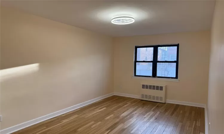 Empty room featuring radiator heating unit and light wood-type flooring