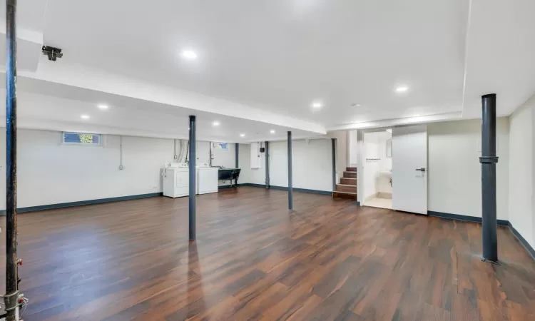 Basement with washing machine and dryer and dark hardwood / wood-style floors