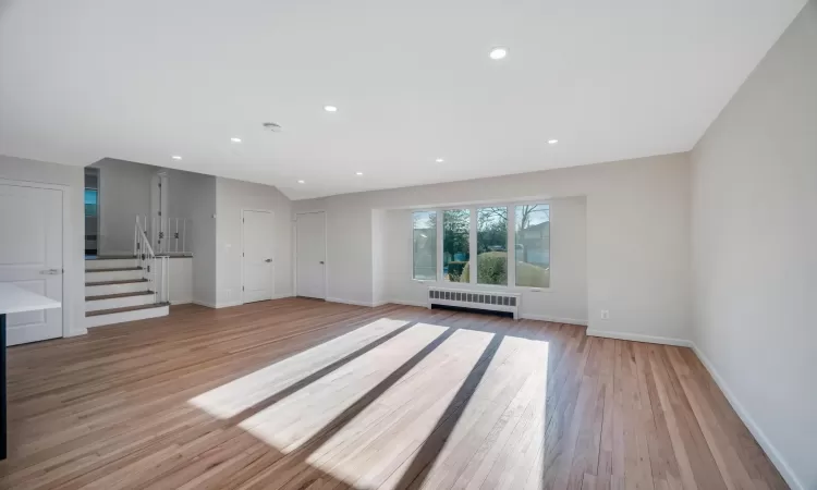 Unfurnished living room featuring light hardwood / wood-style floors and radiator heating unit