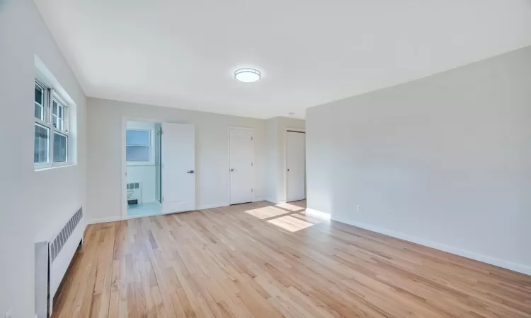 Empty room featuring radiator and light hardwood / wood-style flooring