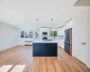 Kitchen featuring radiator heating unit, stainless steel appliances, white cabinets, and decorative light fixtures