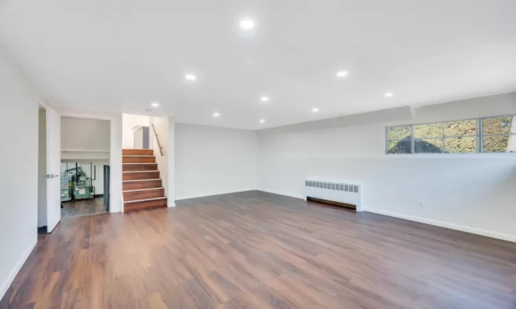 Unfurnished living room with radiator and dark wood-type flooring