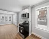 Kitchen featuring white cabinetry, appliances with stainless steel finishes, a wealth of natural light, and a baseboard heating unit