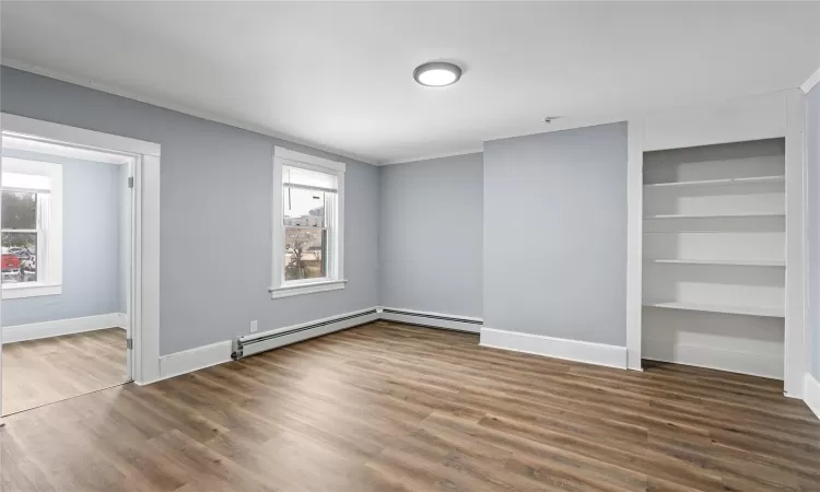 Unfurnished bedroom with crown molding, multiple windows, dark hardwood / wood-style floors, and a closet