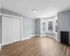 Unfurnished bedroom featuring dark hardwood / wood-style floors, crown molding, radiator heating unit, and a closet