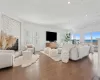 Living room with dark wood-type flooring, a stone fireplace, and ornamental molding