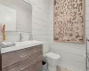 Bathroom with toilet, wooden walls, and vanity