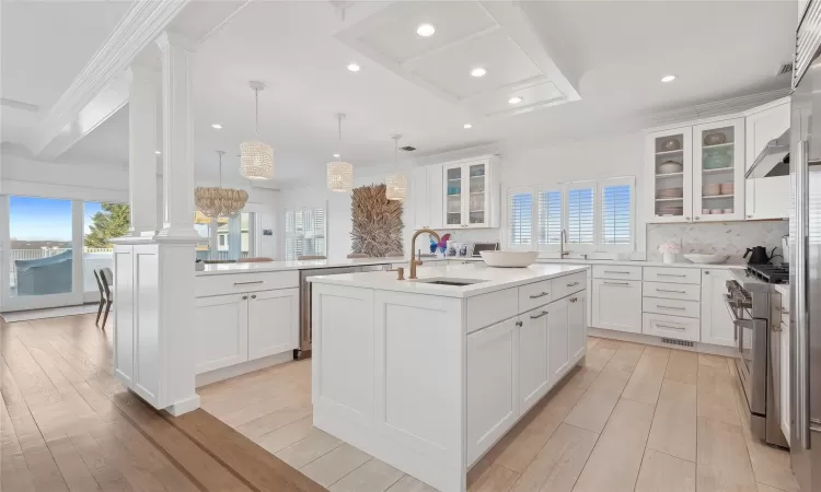 Kitchen featuring a center island with sink, high end stainless steel range oven, hanging light fixtures, and a healthy amount of sunlight