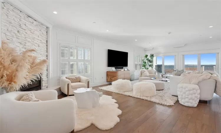 Living room with crown molding, wood-type flooring, and a wealth of natural light