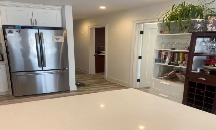 Kitchen featuring stainless steel refrigerator, light wood-type flooring, and white cabinets