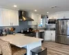 Kitchen with wall chimney range hood, white cabinetry, and stainless steel appliances