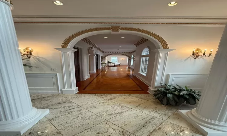 Corridor featuring crown molding and decorative columns