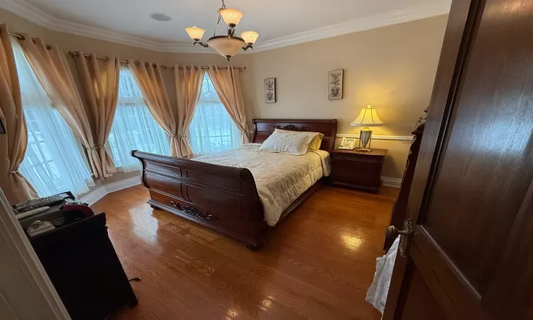 Bedroom with ornamental molding, a chandelier, and wood-type flooring