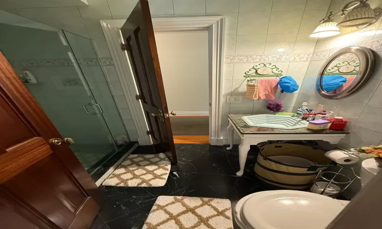 Bathroom featuring tile walls and a shower with shower door