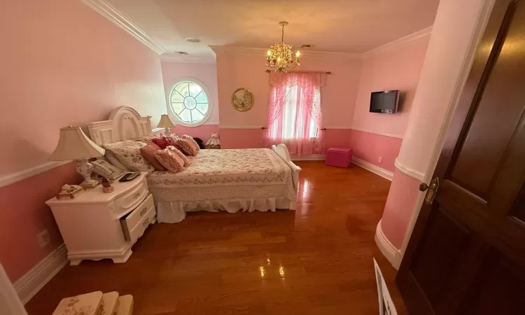 Bedroom featuring dark hardwood / wood-style floors, an inviting chandelier, and ornamental molding