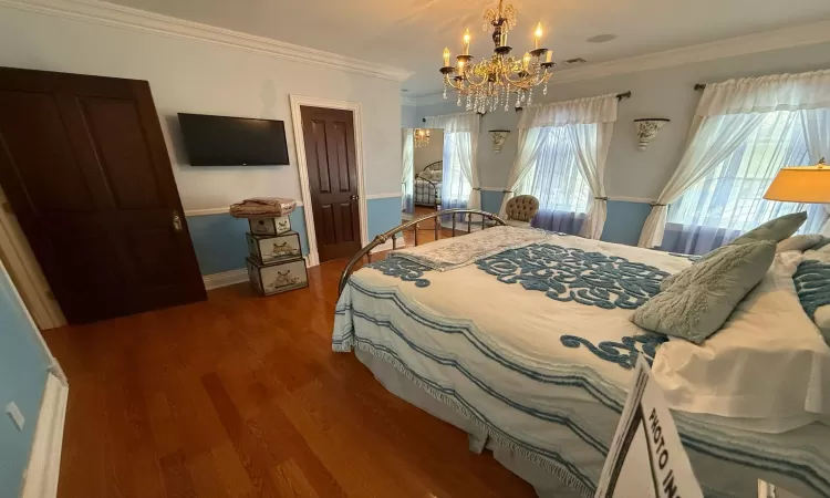 Bedroom featuring dark hardwood / wood-style flooring, a notable chandelier, and ornamental molding