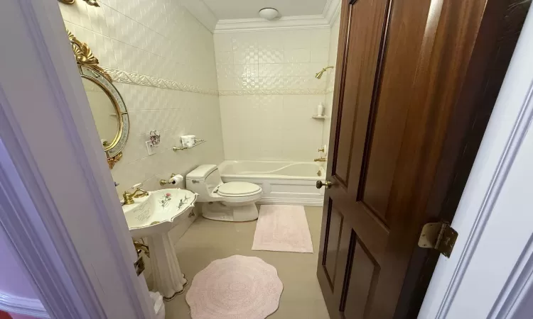 Full bathroom featuring sink, tile walls, tiled shower / bath combo, toilet, and crown molding