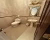 Bathroom featuring toilet, tile walls, tile patterned flooring, and sink