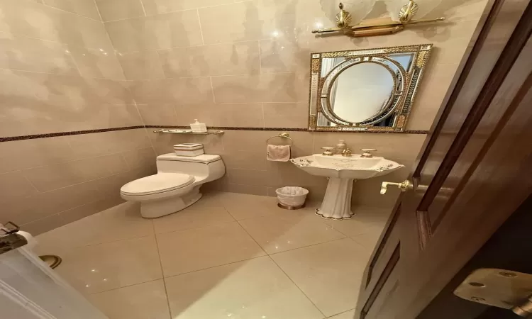 Bathroom featuring toilet, tile walls, tile patterned flooring, and sink