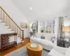 Living room with recessed lighting, wood finished floors, baseboards, high vaulted ceiling, and stairs