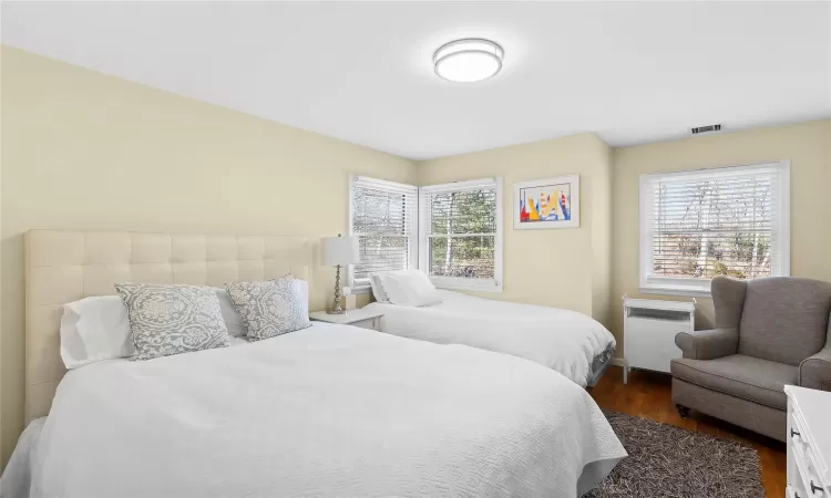 Bedroom with visible vents, multiple windows, and dark wood-type flooring