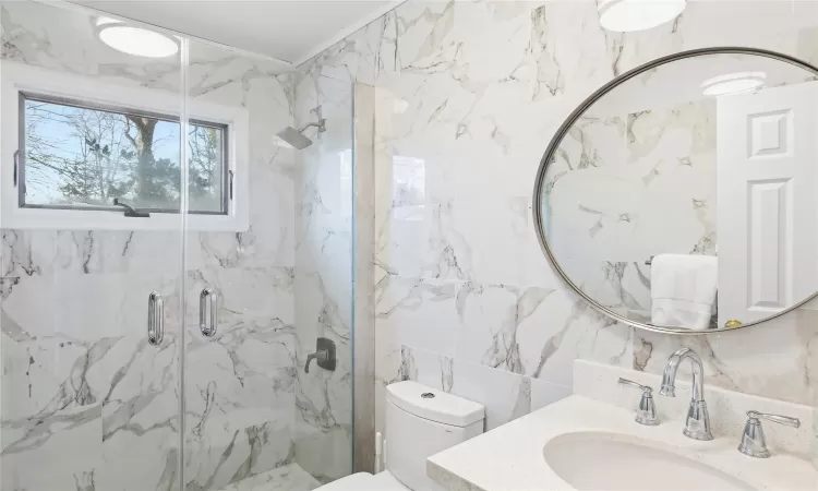 Full bathroom featuring vanity, tile walls, a marble finish shower, toilet, and backsplash