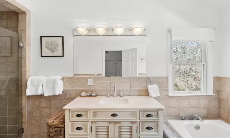 Full bath featuring vanity, tile walls, a bath, and a stall shower