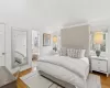 Bedroom featuring light wood-style floors, high vaulted ceiling, and connected bathroom