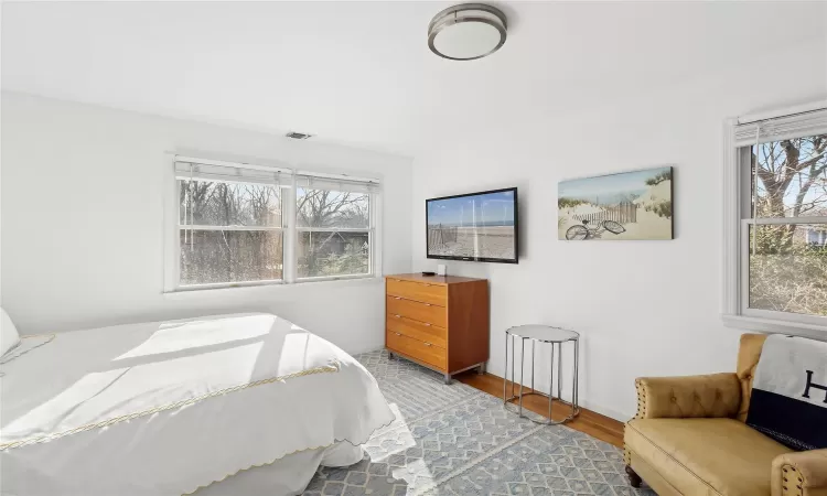 Bedroom with visible vents, baseboards, and wood finished floors