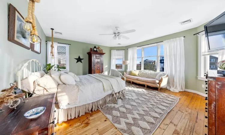 Bedroom featuring light wood-style floors, visible vents, baseboards, and a ceiling fan