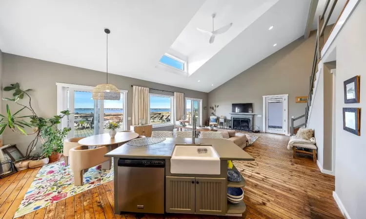 Kitchen with open floor plan, hanging light fixtures, a kitchen island with sink, a fireplace, and stainless steel dishwasher