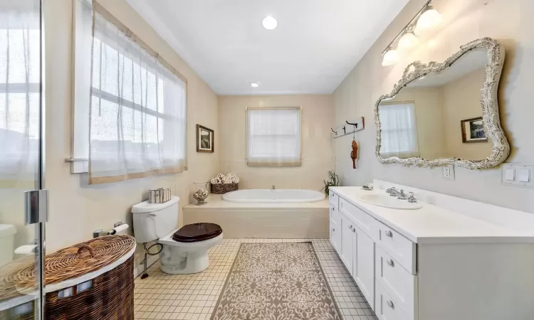 Bathroom featuring a garden tub, toilet, recessed lighting, vanity, and tile patterned floors