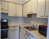 Kitchen featuring stainless steel gas stove, light countertops, under cabinet range hood, white cabinetry, and a sink