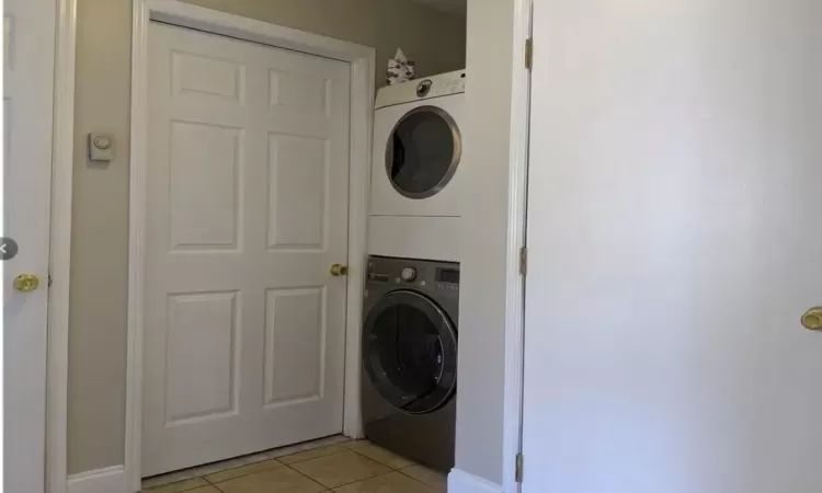 Laundry area with stacked washer / dryer, laundry area, and light tile patterned floors