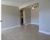 Unfurnished room featuring stacked washer and dryer, light tile patterned floors, baseboards, and a ceiling fan