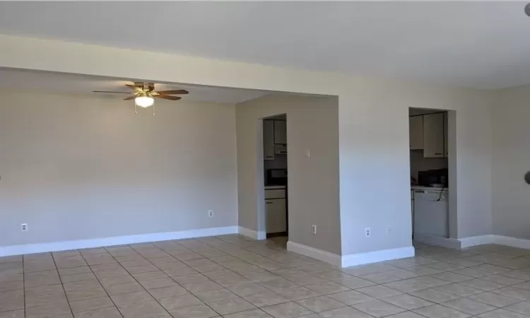 Empty room with light tile patterned floors, ceiling fan, and baseboards