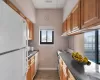 Kitchen featuring dark countertops, white appliances, baseboards, and brown cabinets